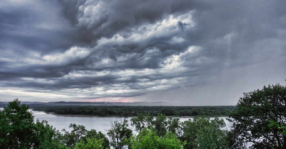 Aerial view of a river and lush trees under dramatic cloudy skies in Maple Springs, MN.