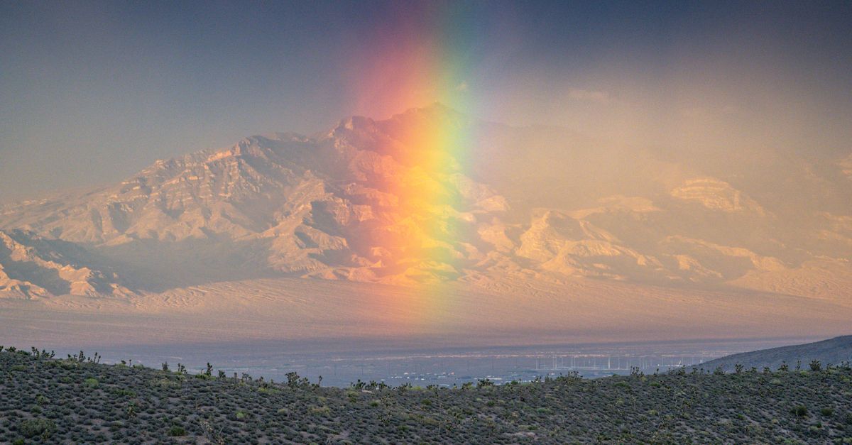 Dramatic mountain landscape featuring a vibrant rainbow over Mount Charleston, Nevada.